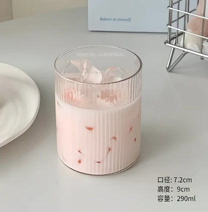 A ribbed clear glass coffee cup filled with pink iced drink and red fruit pieces from decorbites clear glass set