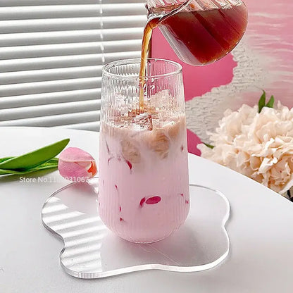 A ribbed clear glass coffee cup filled with a pink iced drink and floating red fruit pieces by decorbites clear glass