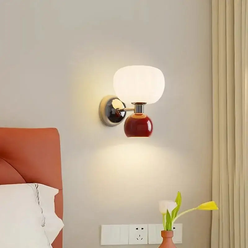 A modern wall lamp with a glossy red ceramic base, chrome arm, and opaque white glass shade for bedroom decorbites cream breeze