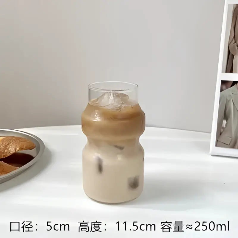 A clear ribbed frosted borosilicate glass cup with a bulbous shape holding iced coffee from decorbites borosilicate glass cups