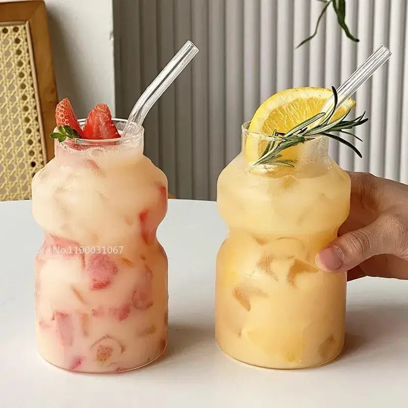 Two ribbed frosted borosilicate glass cups mason jar tumblers filled with pink strawberry and yellow citrus drinks with clear straws