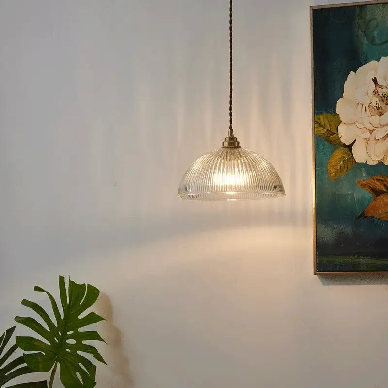 Clear ribbed glass chandelier pendant lights with a brass finish and dark braided cord for bedroom use