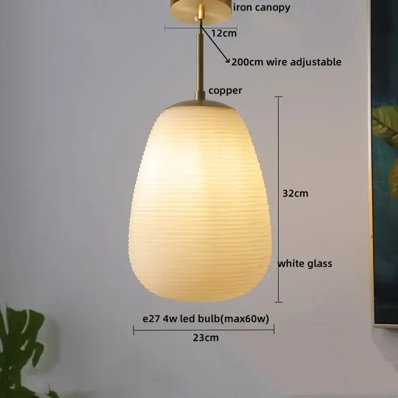 A warm glowing pendant chandelier with ribbed white glass shade and copper led pendant hardware for dining room