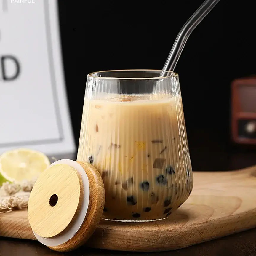 Clear ribbed glass cup filled with iced coffee and black tapioca pearls from a glass cup set with bamboo lid and straw