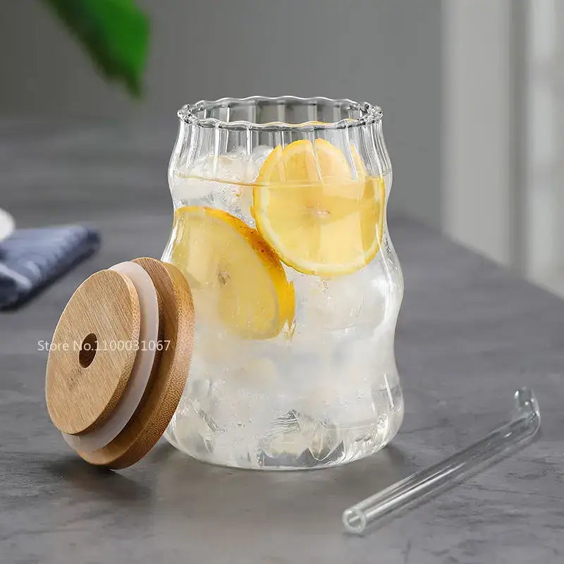 Clear glass cup with fluted rim and textured body filled with ice and lemon, part of decorbites glass cup set with bamboo lids and straws