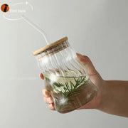 Clear ribbed glass cup with bamboo lid and lip straw filled with water and fresh rosemary for decorbites glass cup use