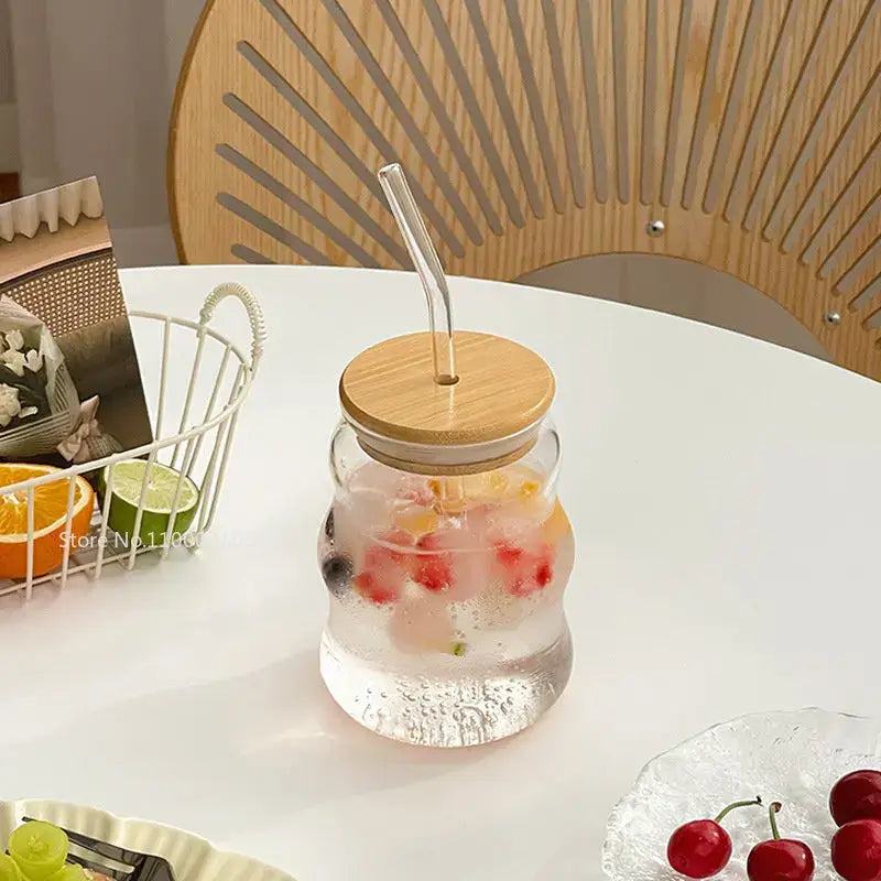 Ribbed clear glass cup with bamboo lid and curved lip straw filled with ice and fruit decorbites glass cup
