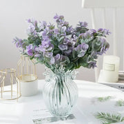 A clear ribbed glass eucalyptus leaves vase holding artificial lavender and green eucalyptus leaves for living room decor