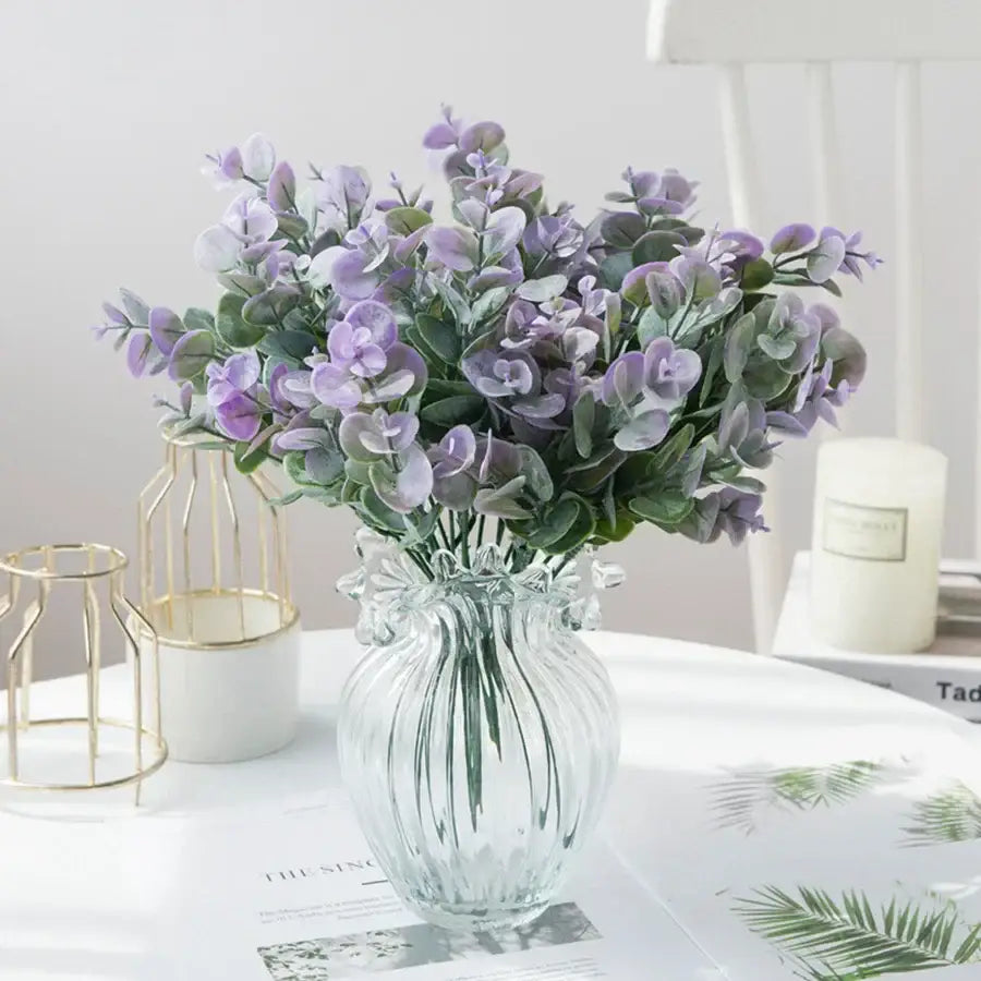 A clear ribbed glass eucalyptus leaves vase holding artificial lavender and green eucalyptus leaves for living room decor