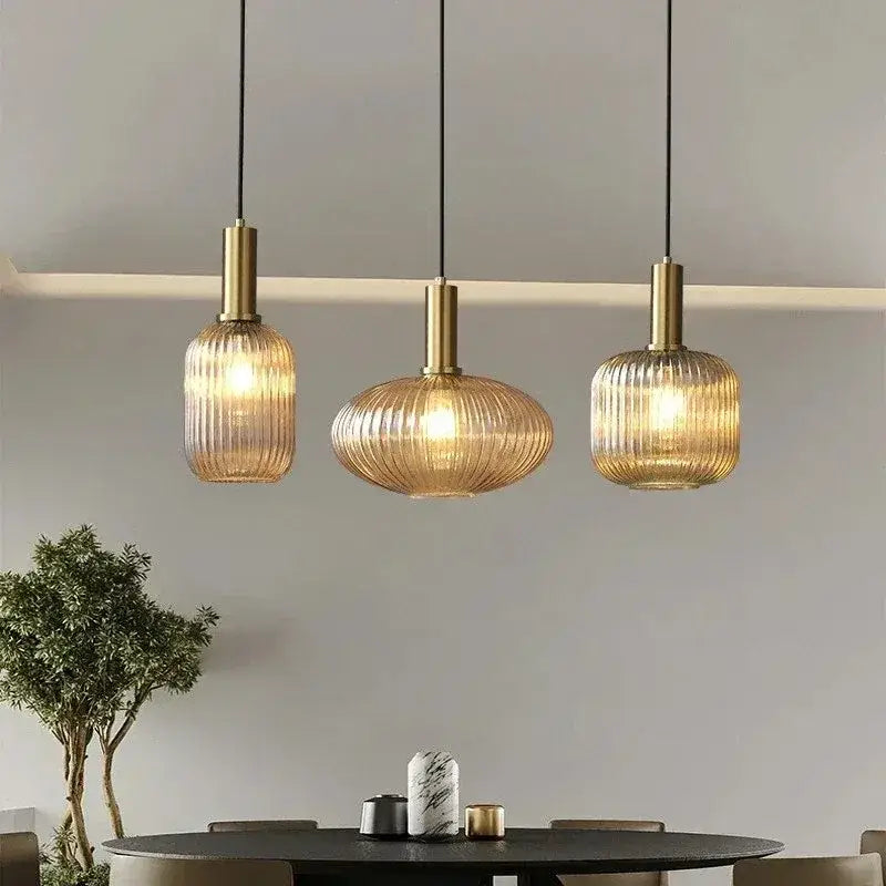 Three elegant amber ribbed glass pendant lights with brass accents in a modern dining room pendant light setup
