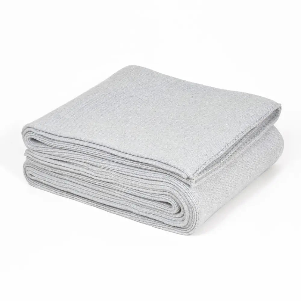A neatly folded light gray microfiber cloth with visible stitching beside a ribbed gray organic cotton weighted blanket