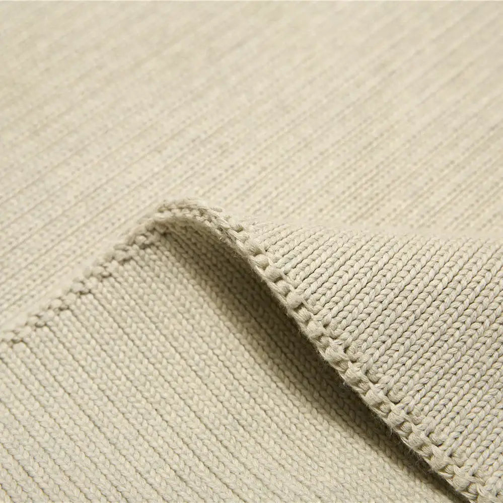 Beige ribbed knit fabric with soft texture and finished edge on a ribbed gray organic cotton weighted blanket
