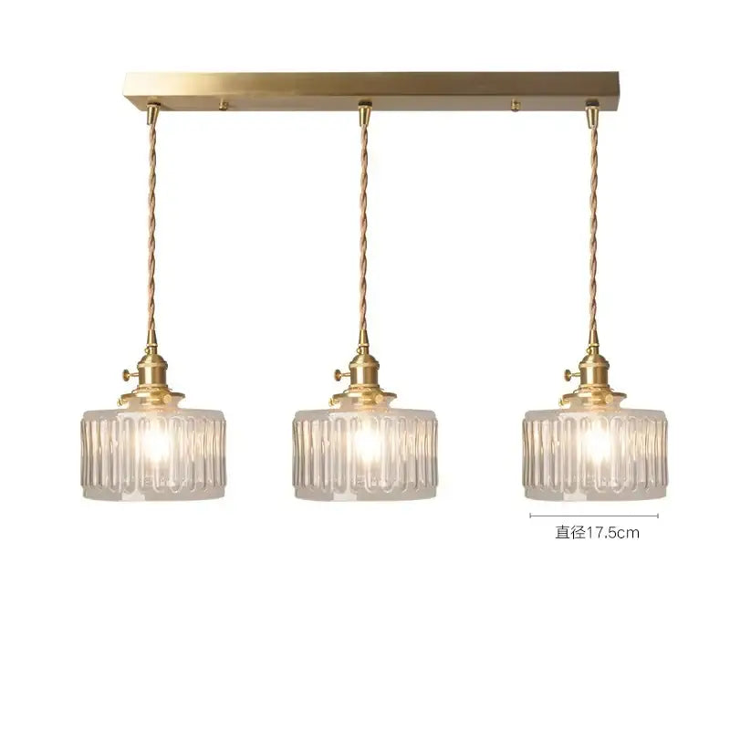 Gold-toned three-light pendant light with clear ribbed glass shades and twisted brass cords for elegant green glass pendant decor