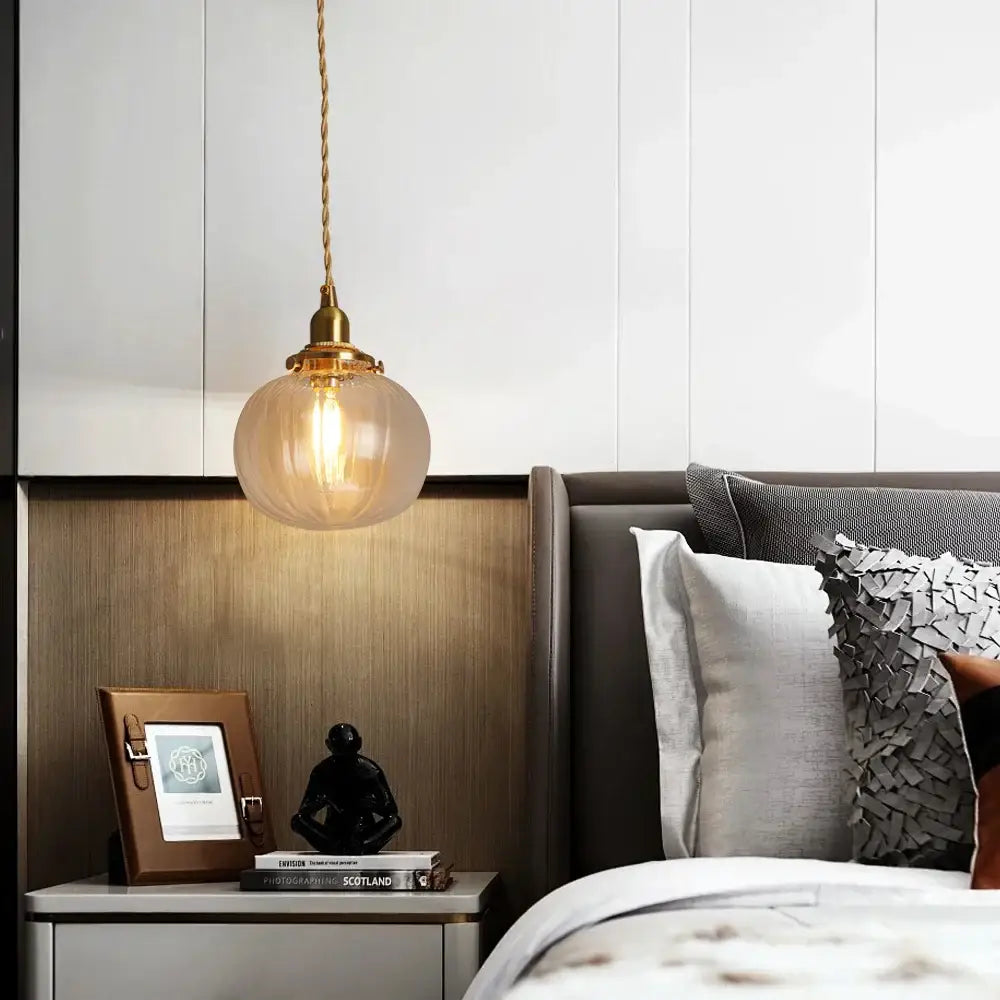 A warm-toned ribbed green glass pendant light with brass hardware hangs above a bedside table decorbites green pendant