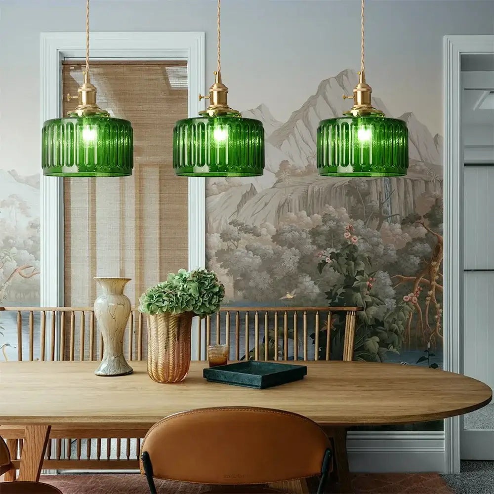 Three emerald green ribbed glass pendant lights with brass fixtures hang above wooden dining table decorbites green pendant