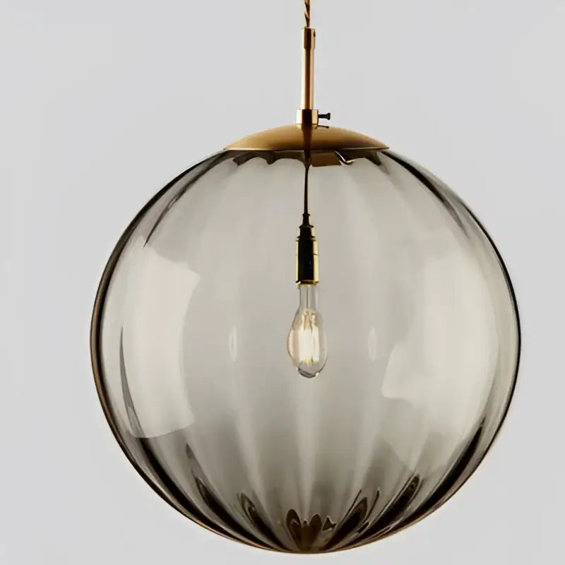A sleek smoked glass globe pendant light with brass top and iron finish ideal for dining room lighting