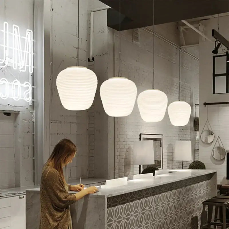 White ribbed off-white glass cocoon pendant light by decorbites hanging from ceiling for dining room decor