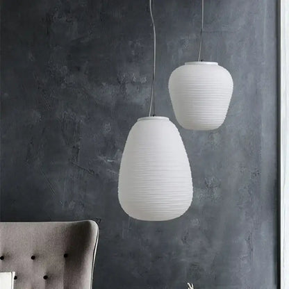 Two white ribbed off-white glass cocoon pendant lights hang against a dark gray wall for dining room decorbites pendant light
