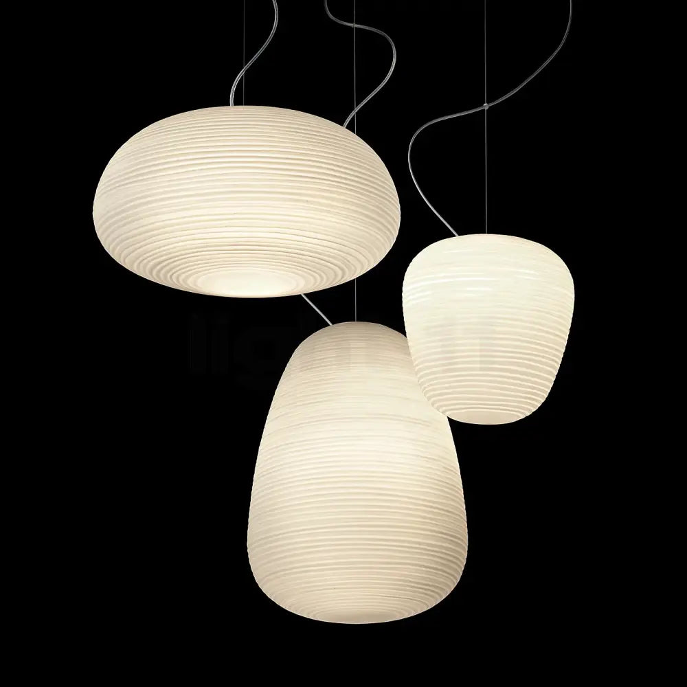 Three off-white ribbed glass whorl pendant lights with curved metal cords for kitchen decor against black background