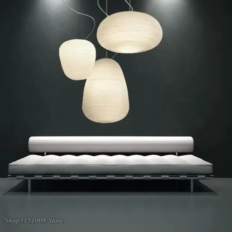 Three elegant off-white ribbed glass whorl pendant lights hang above a minimalist sofa for kitchen decor