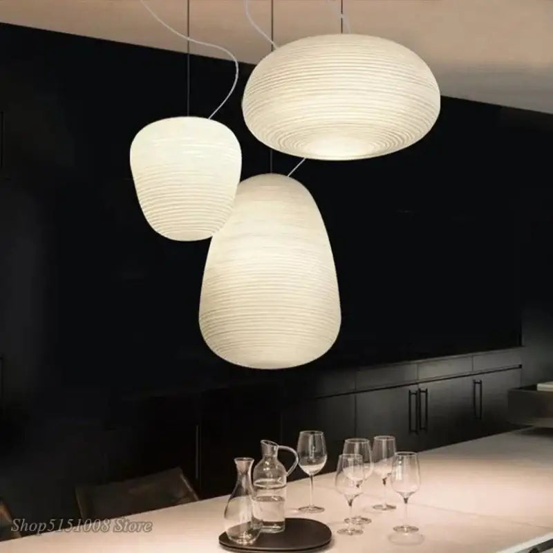 Three off-white glass whorl pendant lights with ribbed patterns hang in a minimalist kitchen pendant light decor