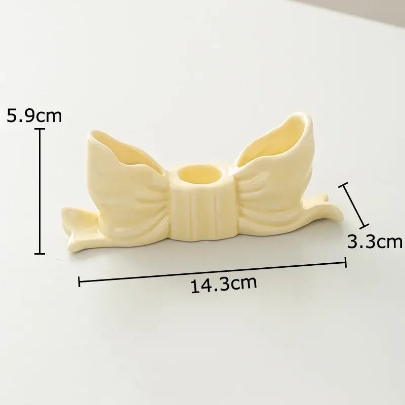 Cream-colored ceramic bowknot candle holder with two side compartments and central opening for decorbites desk decor