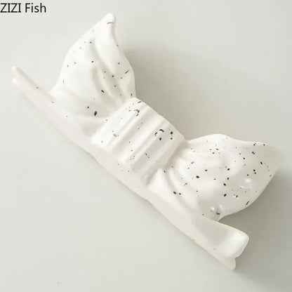 White ceramic fish-shaped candle holder with black speckles and ribbed texture for decorbites bowknot candle holder decor