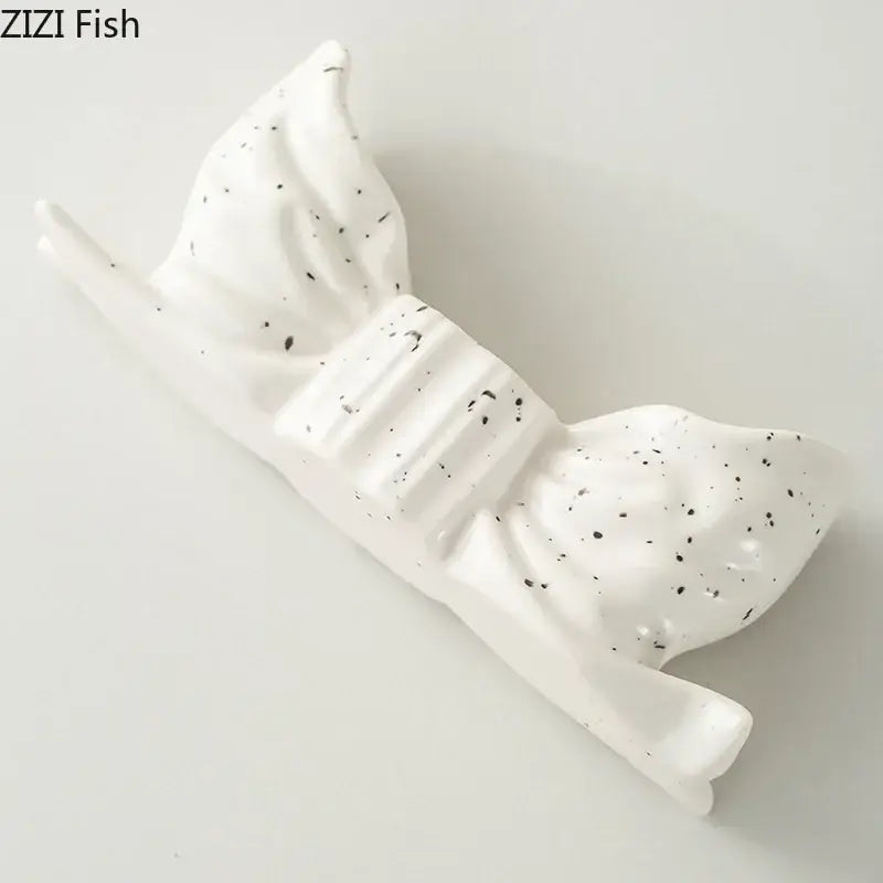 White ceramic fish-shaped candle holder with black speckles and ribbed texture for decorbites bowknot candle holder decor