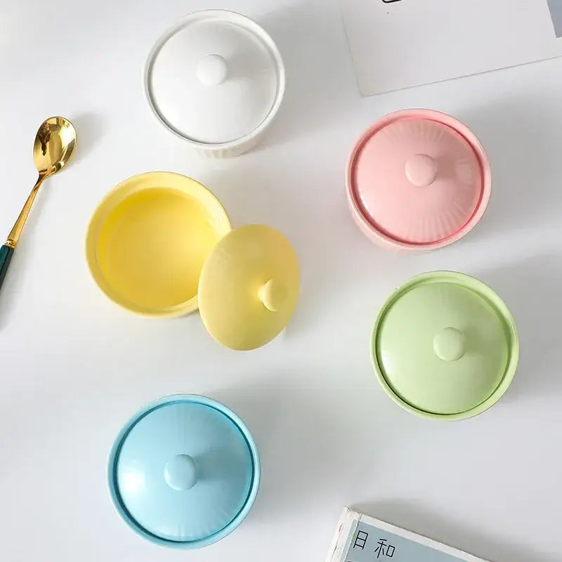 Pastel-colored decorbites ceramic dessert lidded jars in yellow pink green and blue including a ribbed pink ceramic dessert bowl with lid
