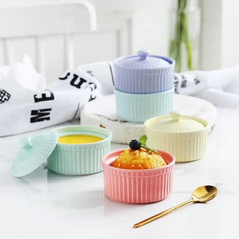 Pastel pink ribbed decorbites ceramic dessert bowl with lid filled with golden custard and a blueberry garnish