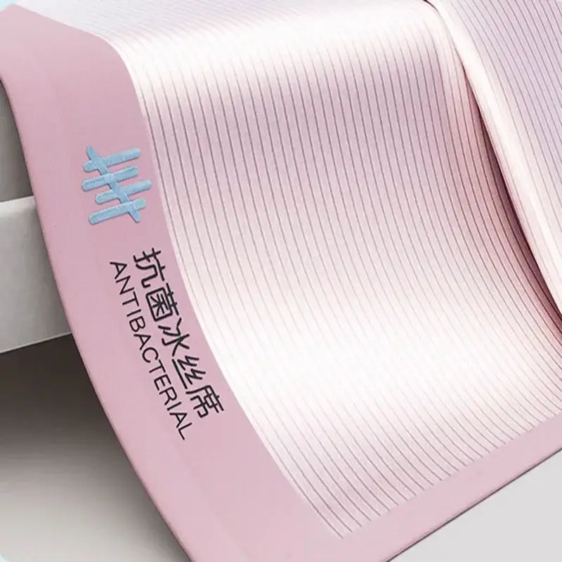 Ribbed pink antibacterial bed mat set with soft textured pleats and light blue logo for bedroom use
