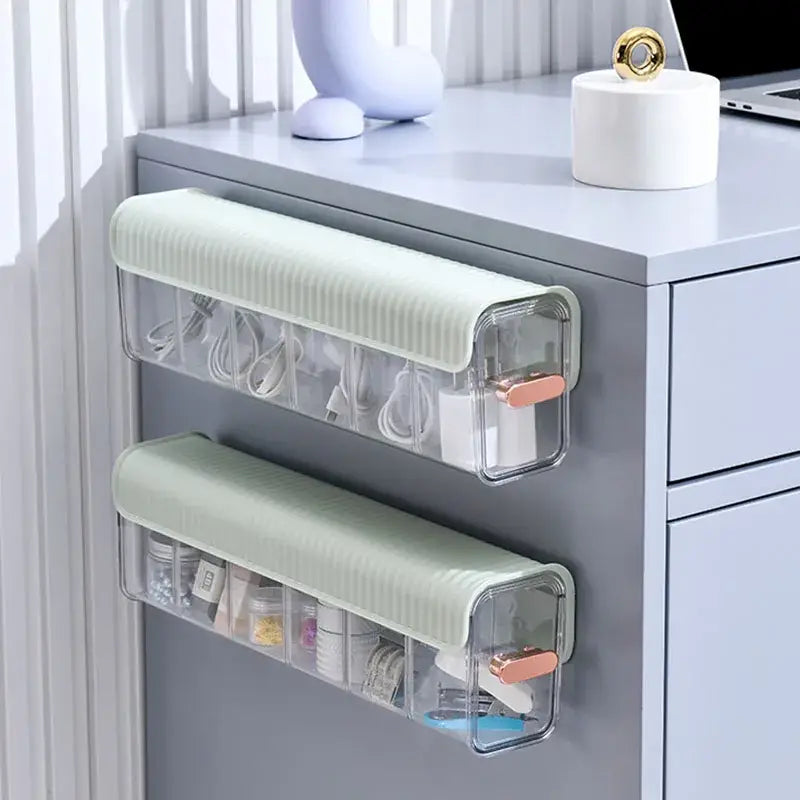 Two translucent plastic data cable organizer boxes with sage green ribbed tops and rose gold handles mounted on gray cabinet