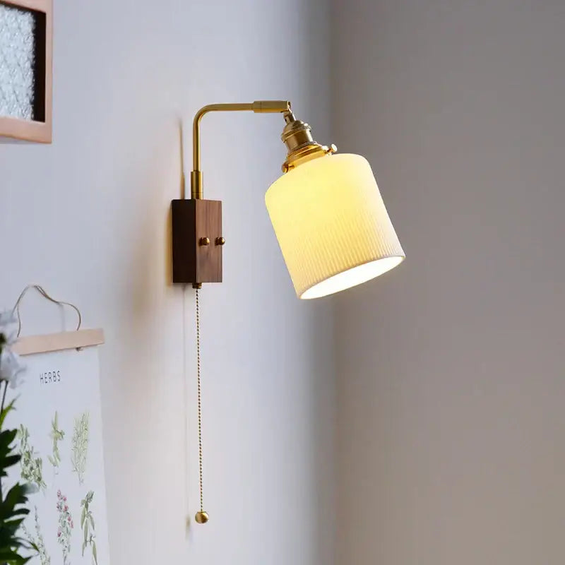 A warm-toned brass led wall lamp with a ribbed off-white glass shade and wooden base for bedroom mirror lighting