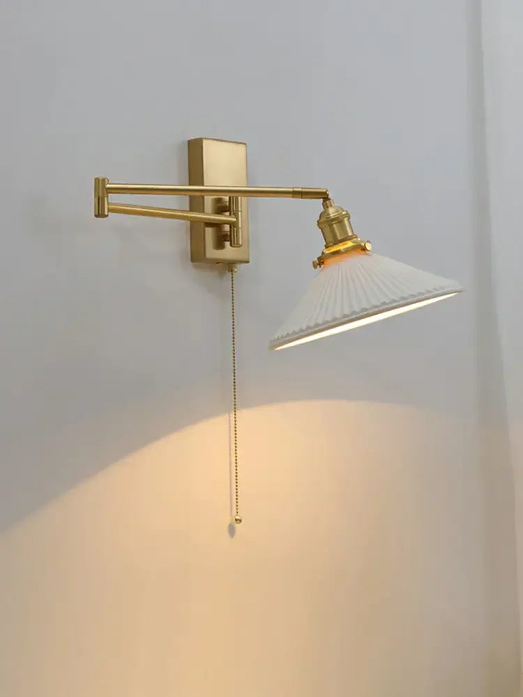 Gold-finished wall sconce with white pleated glass shade and ornate brass swing arm from decorbites brass swing collection