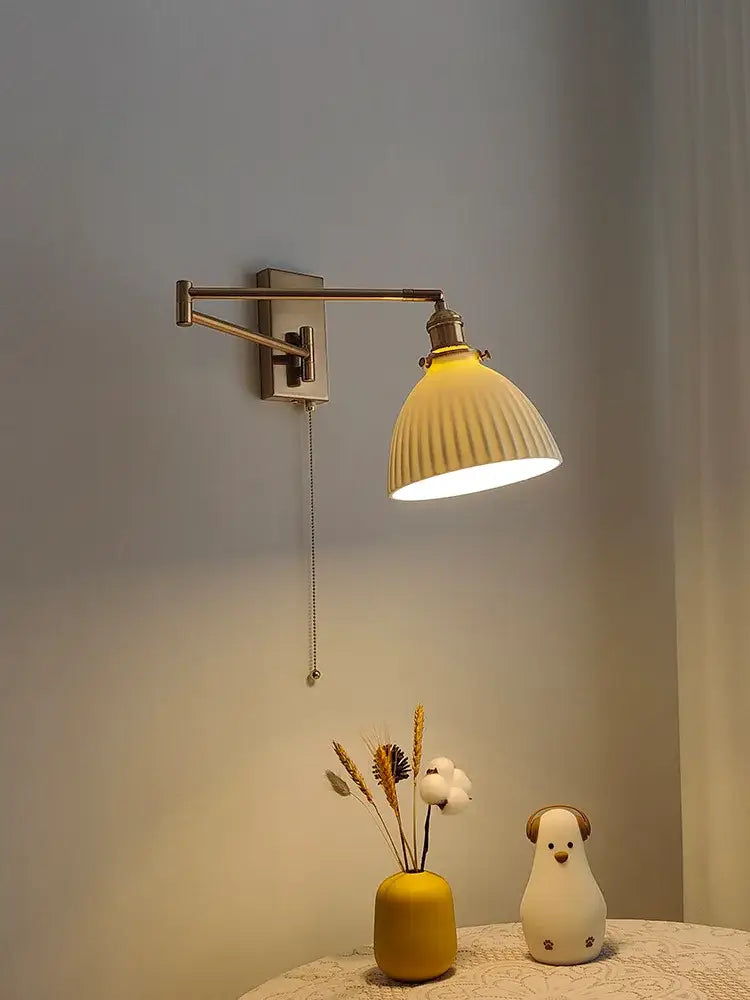 A ribbed yellow ceramic lampshade wall sconce with a decorbites brass swing arm for adjustable bedroom lighting