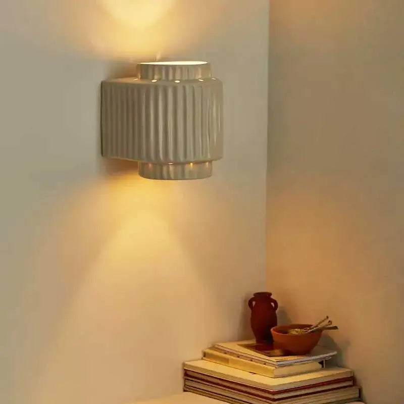 A sleek cream white resin wall sconce with ridged vertical lines and tiered design decorbites cream white bedroom light