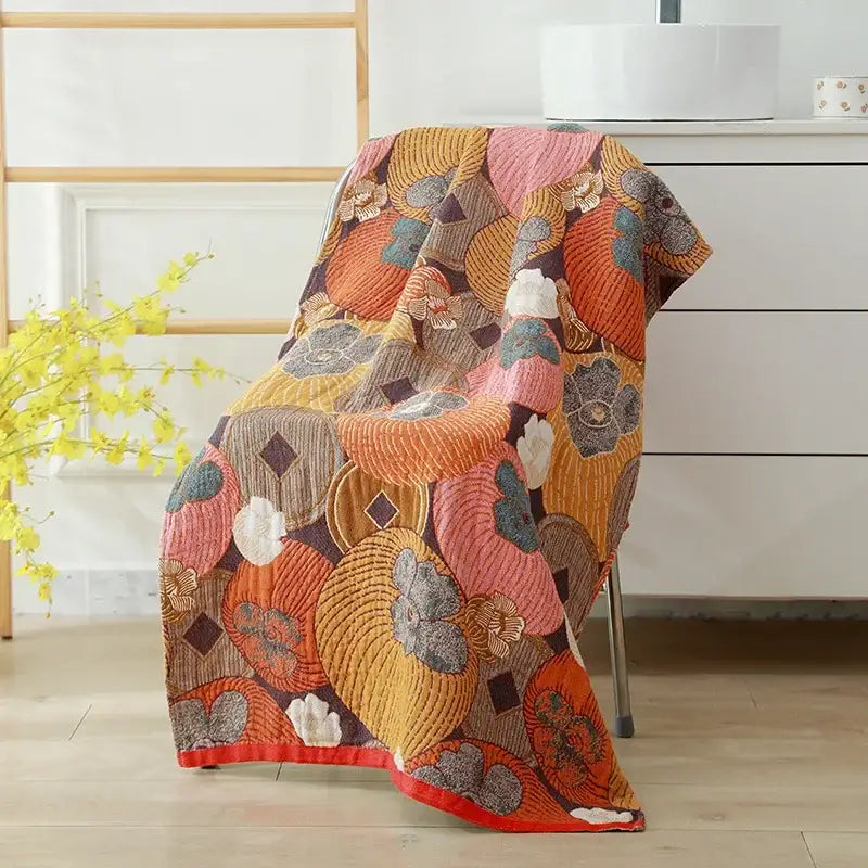 A vibrant quilted cotton bath towel with bold orange pink and mustard-yellow floral patterns for bathroom decor