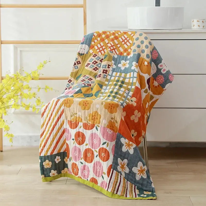 A colorful patchwork cotton bath towel with floral and geometric patterns in orange pink blue green and yellow for bathroom decor