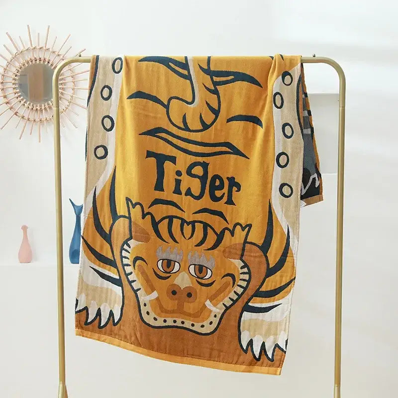 A vibrant yellow cotton bath towel featuring a bold tiger face and dark lettering for bathroom decor