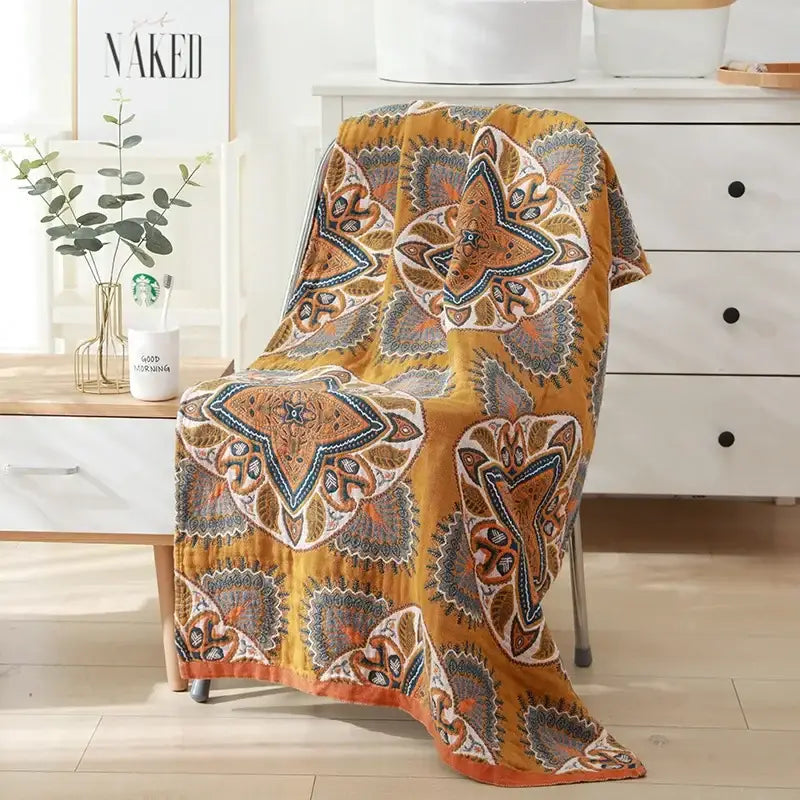 A cozy mustard-yellow quilted cotton bath towel with intricate paisley patterns in brown blue and cream for bathroom decor