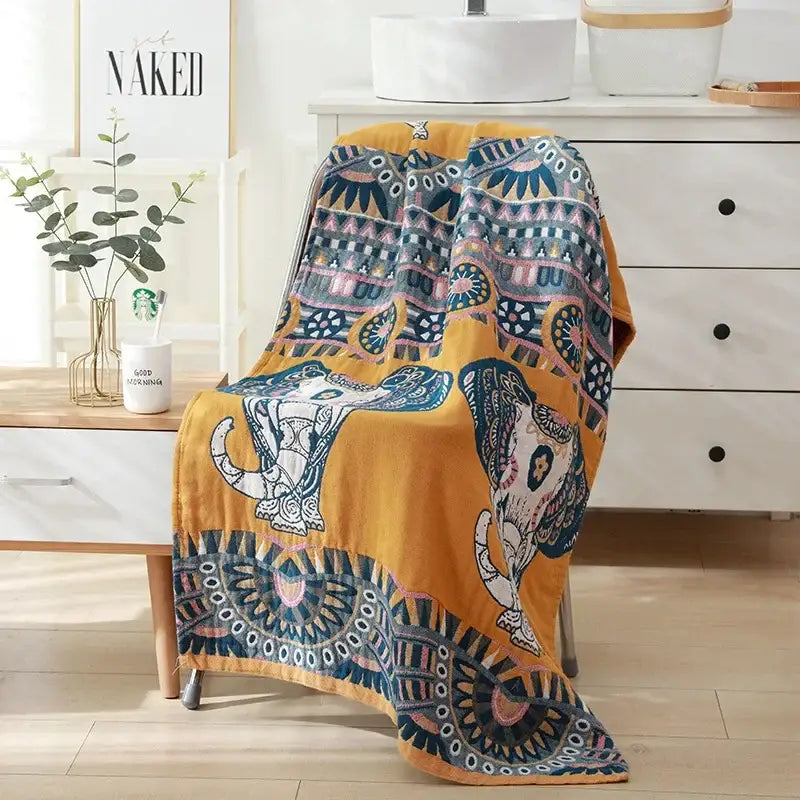 A cozy mustard-yellow cotton bath towel with intricate blue pink and white elephant mandala designs for bathroom decor