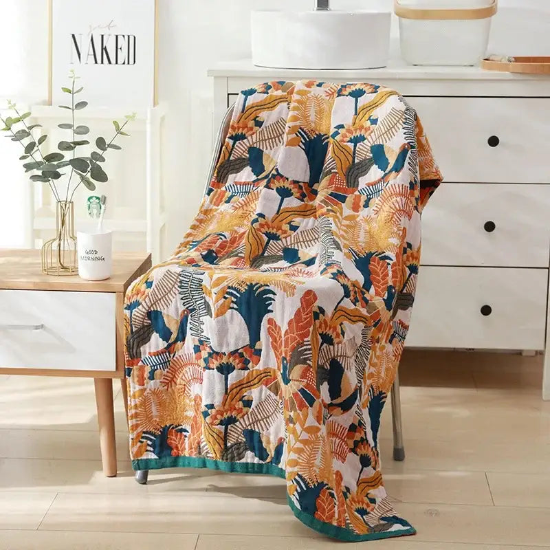A cozy cotton bath towel with a quilted tropical leaf and floral pattern in orange teal and cream for bathroom decor