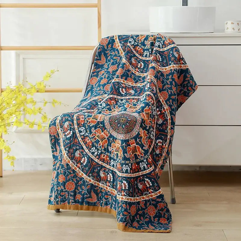 A navy blue cotton bath towel with intricate orange and white elephant patterns floral motifs and golden-brown hem