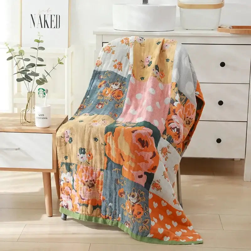 A soft cotton bath towel with a vibrant floral and heart patchwork design in orange pink blue and white for bathroom decor