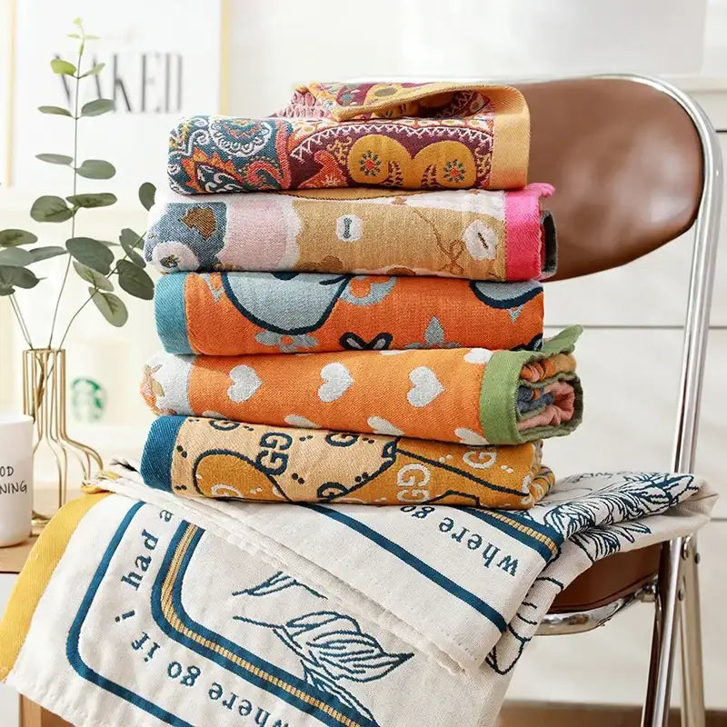 Stack of colorful patterned cotton bath towels featuring romantic beige and black floral designs for bathroom decor