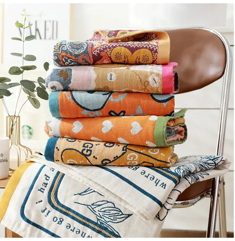 Stack of colorful patterned cotton bath towels with embroidered romantic beige and black floral designs for bathroom decor