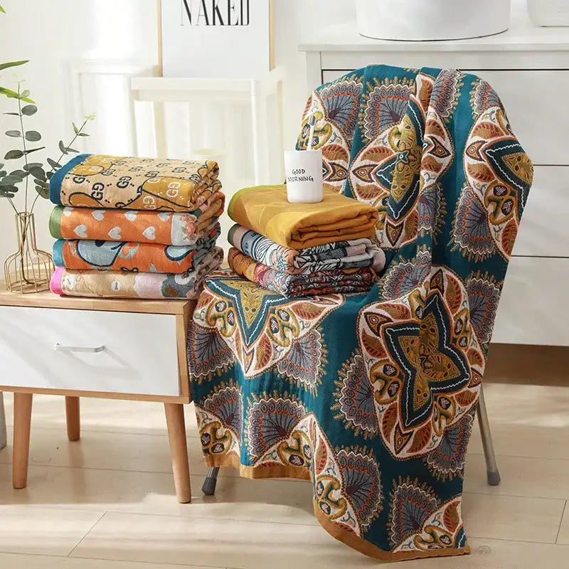 Teal and gold patterned quilted throw blanket with intricate mandala designs complementing cotton bath towel decor