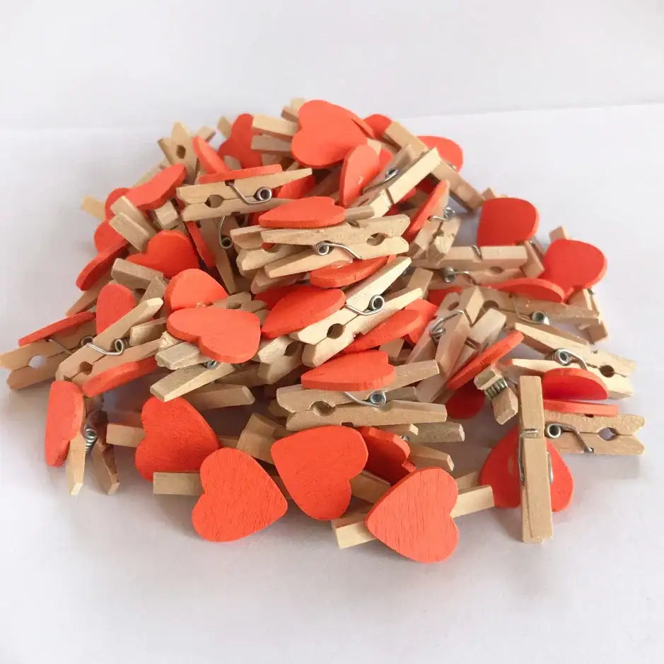 A pile of romantic heart shape wood clips with vibrant orange painted tops and natural wood bodies for bedroom decor