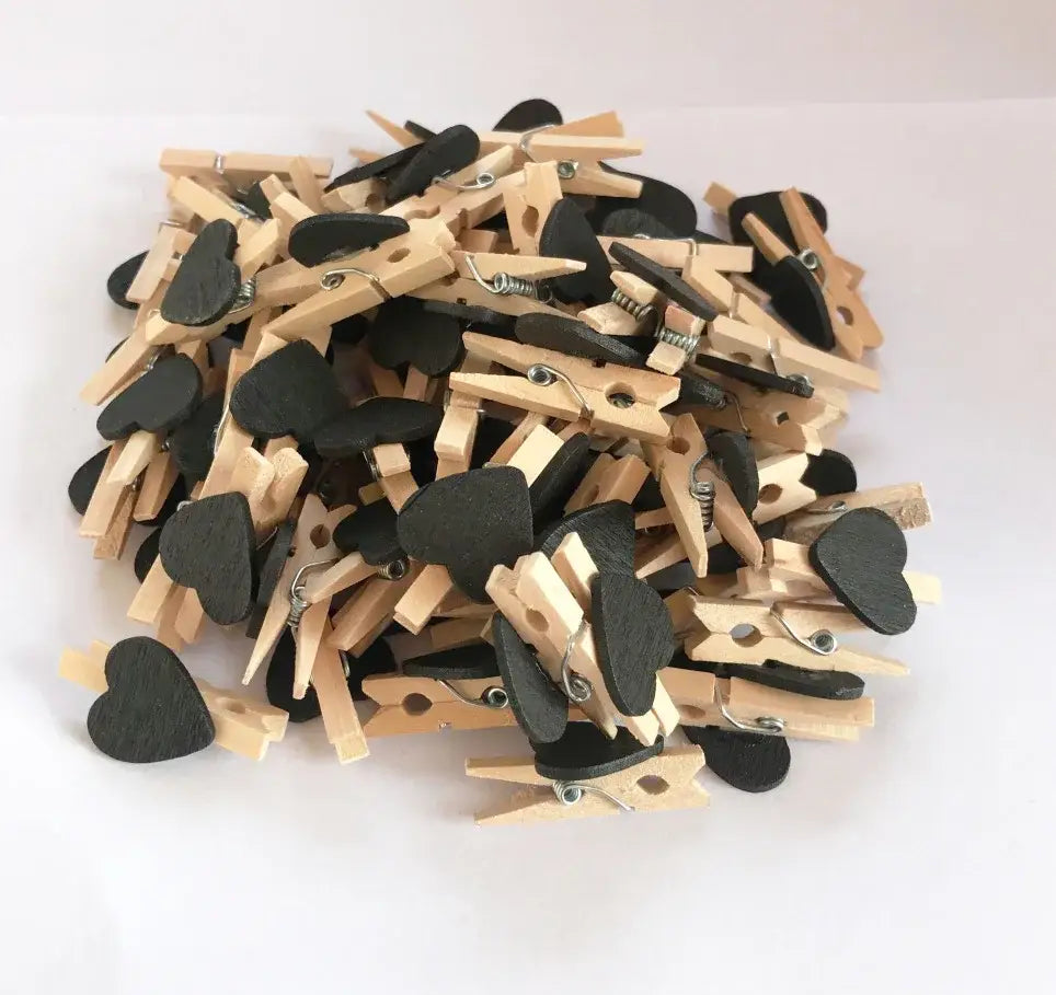 A pile of romantic heart shape wood clips made of wood with black painted centers and metal springs for decor
