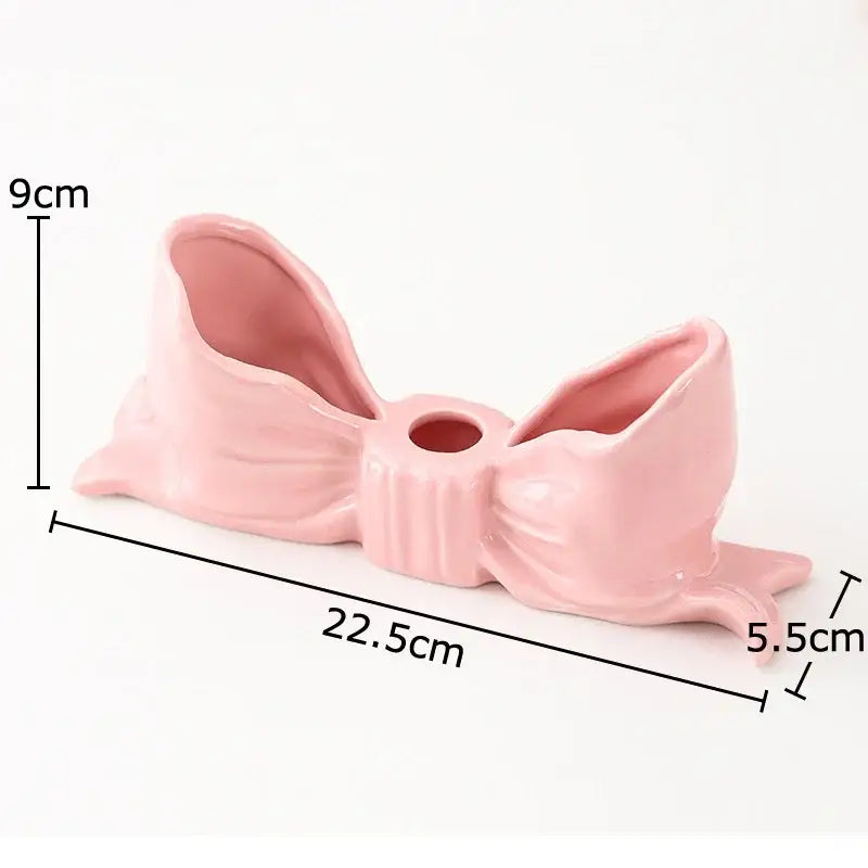Glossy pink ceramic candle holder shaped like a ribbed bowknot with a central hole ideal for dining room decorbites bowknot ceramic